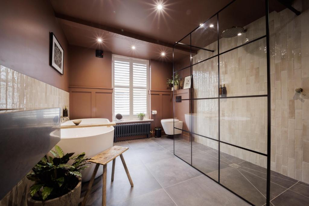 a bathroom with a tub and a toilet and a sink at The Silk Rooms, at The Freemasons Inn in Knutsford