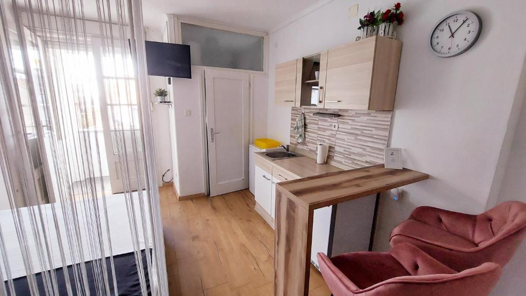 eine kleine Küche mit zwei Stühlen und einer Uhr an der Wand in der Unterkunft Studio Apartment 'Dream' in Šibenik