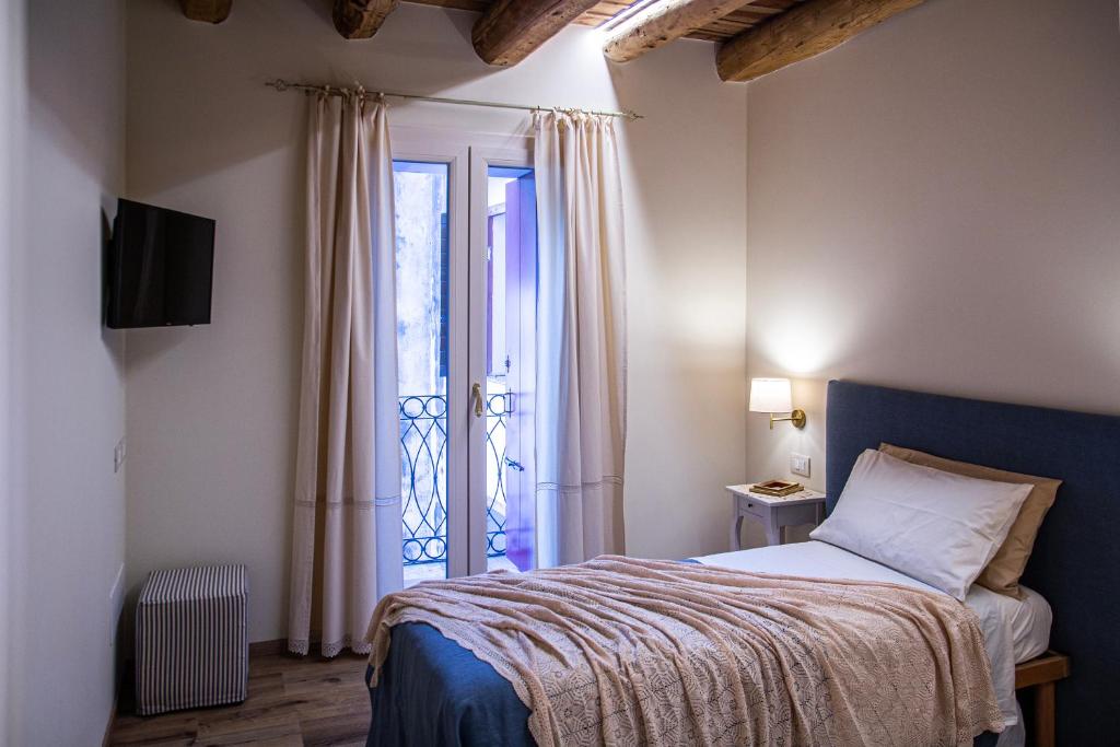 um quarto com uma cama e uma grande janela em Alloggi I Calieroni em Valstagna