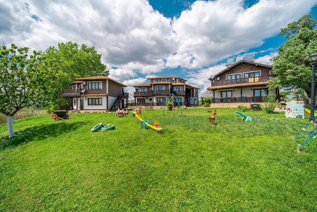 a yard with a playground in the grass with houses at Hotel Complex Zlatnata Ribka in Durankulak
