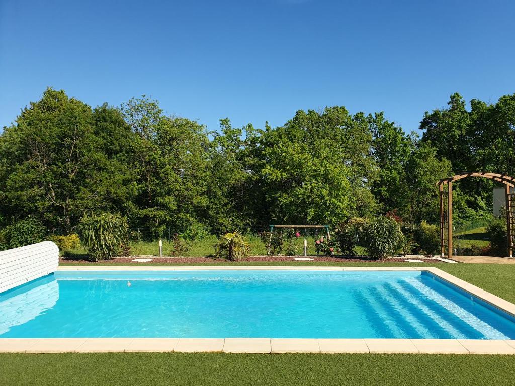 a blue swimming pool in a yard with trees at AC Interlude in Castelnau-de-Montmiral