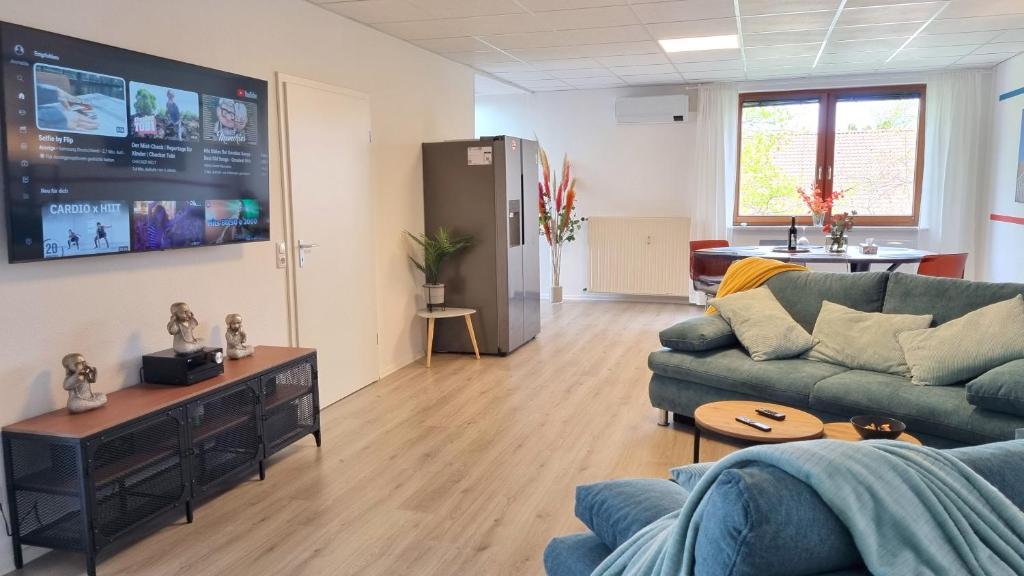 Wohnung: Workaholic bis 6 Personen, Klima, 3x TV في Cremlingen: غرفة معيشة مع أريكة وتلفزيون بشاشة مسطحة