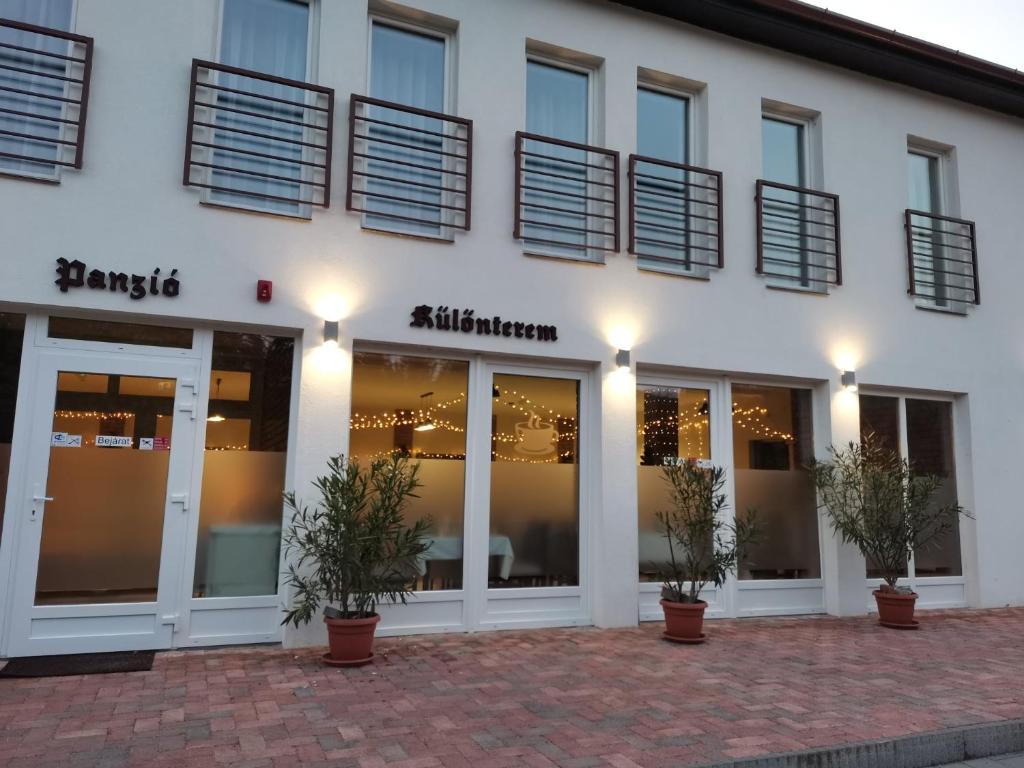 a white building with potted plants in front of it at Privát Fogadó és Étterem in Bükkszentkereszt