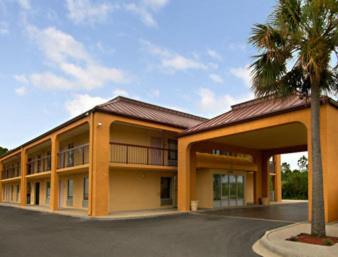 a building with a palm tree in front of it at Days Inn by Wyndham Moss Point Pascagoula in Moss Point