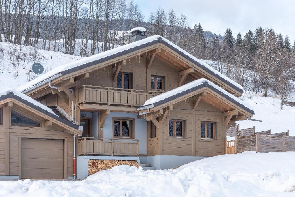 a wooden house with snow on the roof at Chalet Talini in Les Gets