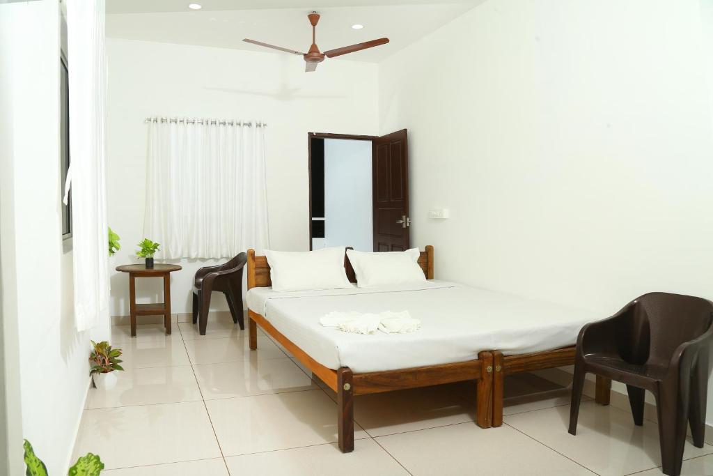 een slaapkamer met een bed en stoelen erin bij Bethesda Inn in Cochin