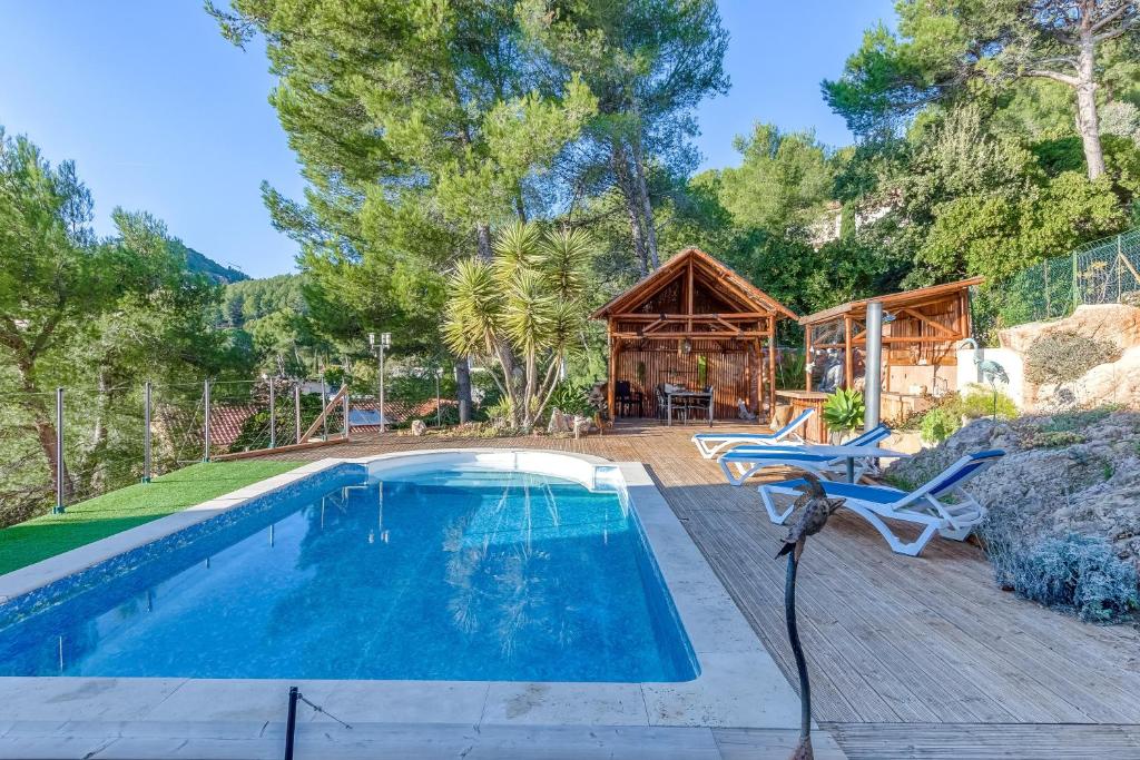 een zwembad met een houten terras en een huis bij Villa enchantée du mont des oiseaux in Hyères