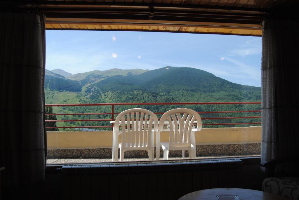 dos sillas blancas sentadas junto a una ventana con montañas en Apartamentos SNÖ Edelweiss, en Cerler