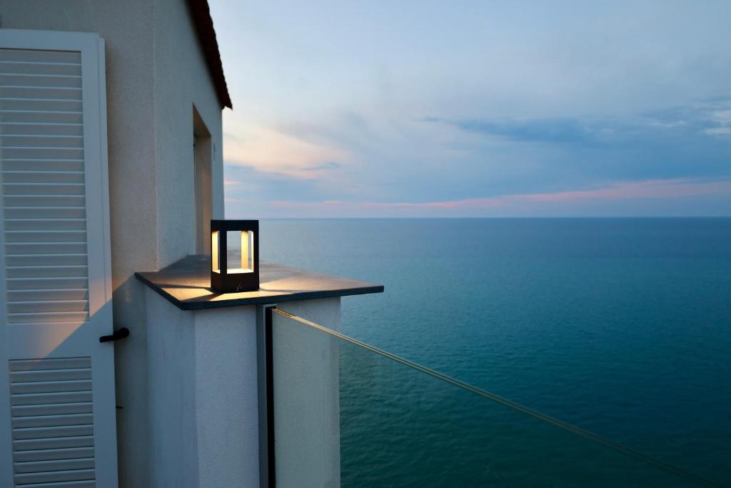 een kaars op een richel op een balkon met uitzicht op de oceaan bij Colombo Suites in Peschici