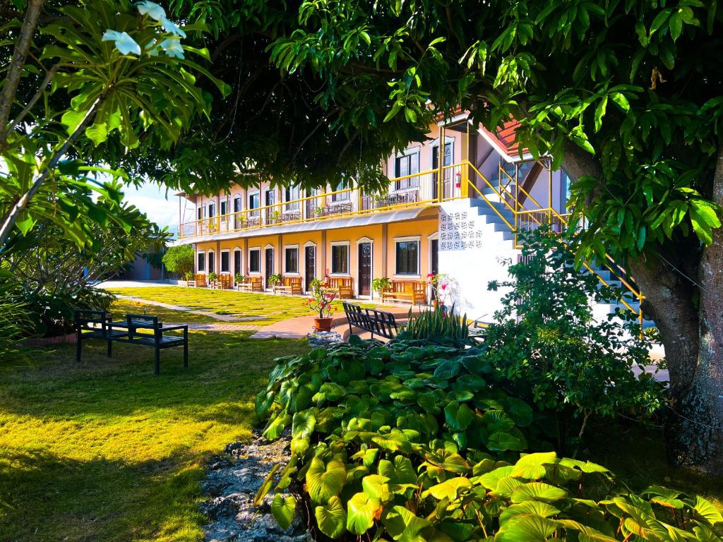 a large yellow building with a tree in front of it at La Plumerias in Moalboal