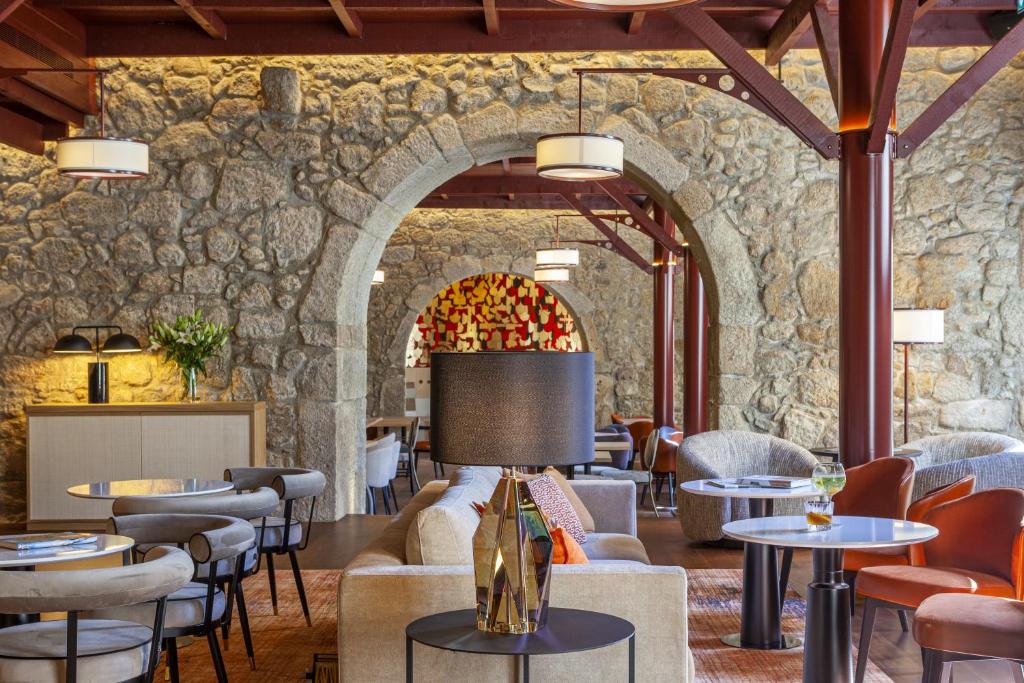 un restaurante con una pared de piedra, mesas y sillas en Hotel das Virtudes, en Oporto