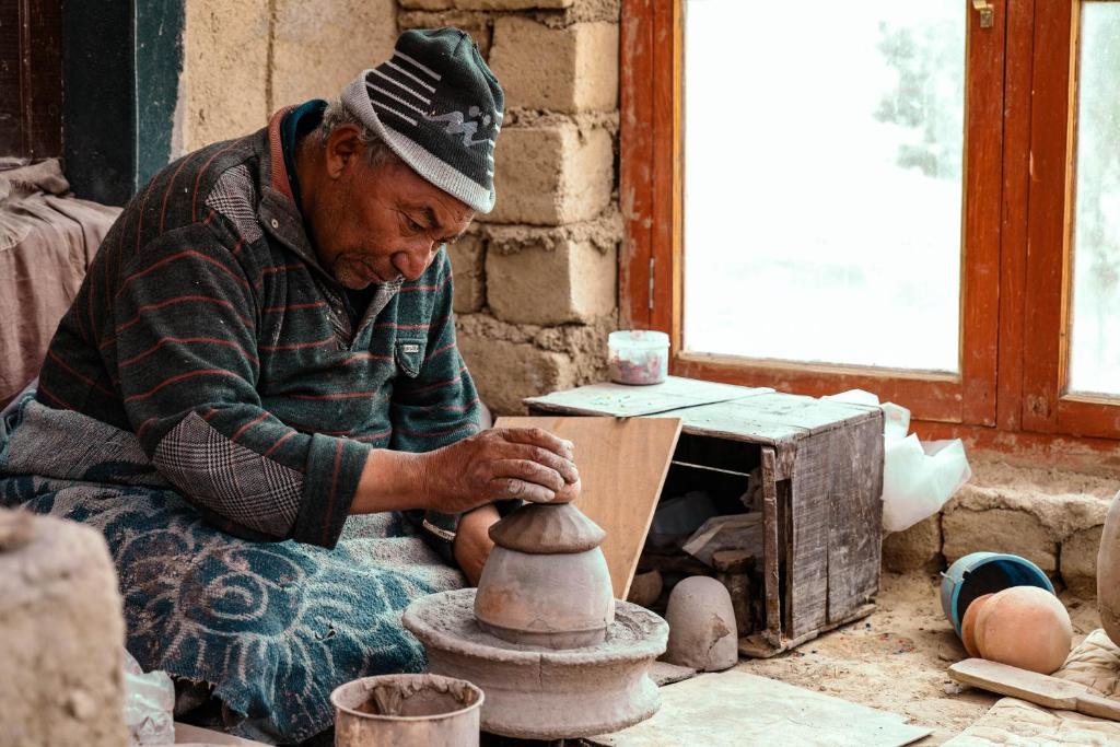 een man die een vaas maakt op een aardewerkwiel bij Likir Pottery Homestay - Likir Village - Sham Valley in Leh