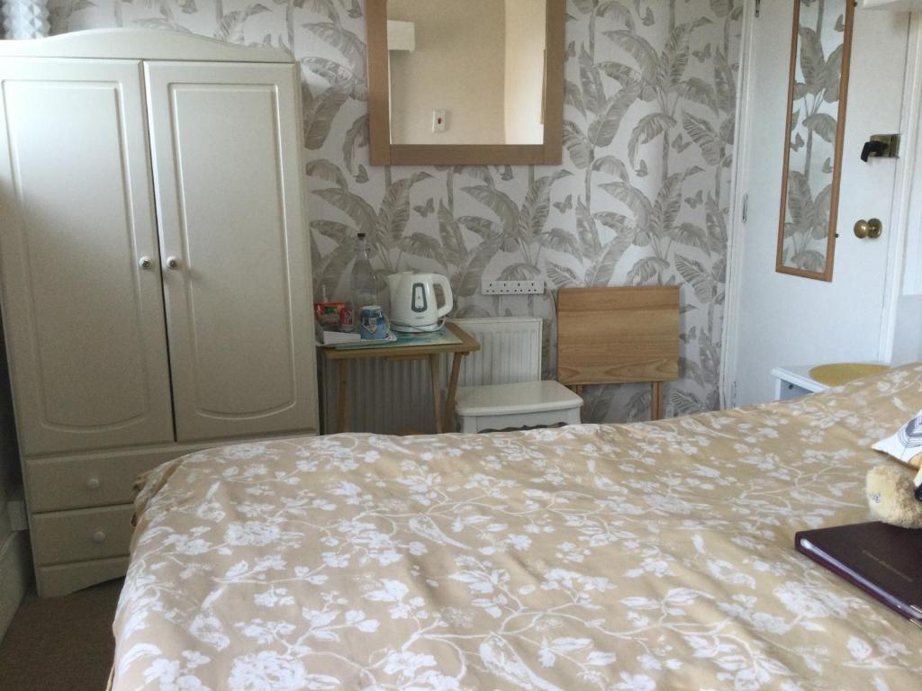 a bedroom with a bed and a dresser and a cabinet at Arun Sands Rooms in Littlehampton