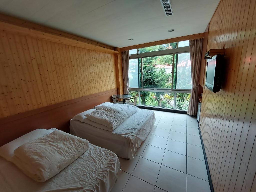 two beds in a room with a large window at Very Happy Homestay in Pingxi