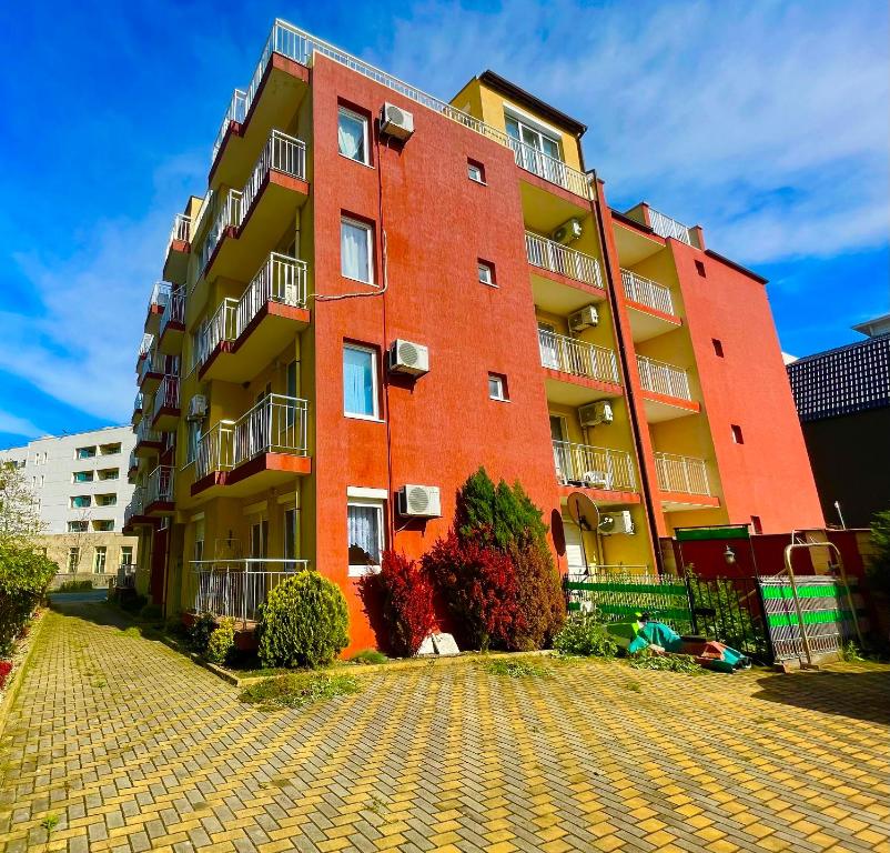 ein rotes Backsteingebäude in einer Kopfsteinpflasterstraße in der Unterkunft North Beach Apartments in Primorsko