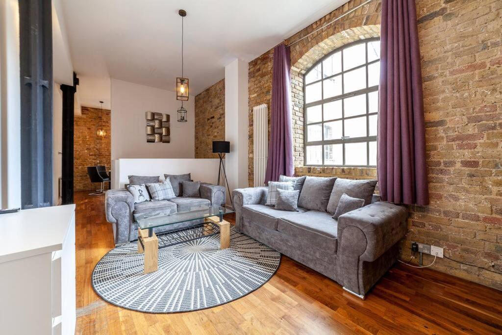 sala de estar con sofá y pared de ladrillo en Stunning Loft-Style Duplex 2 BDR Apt in Bow en Londres