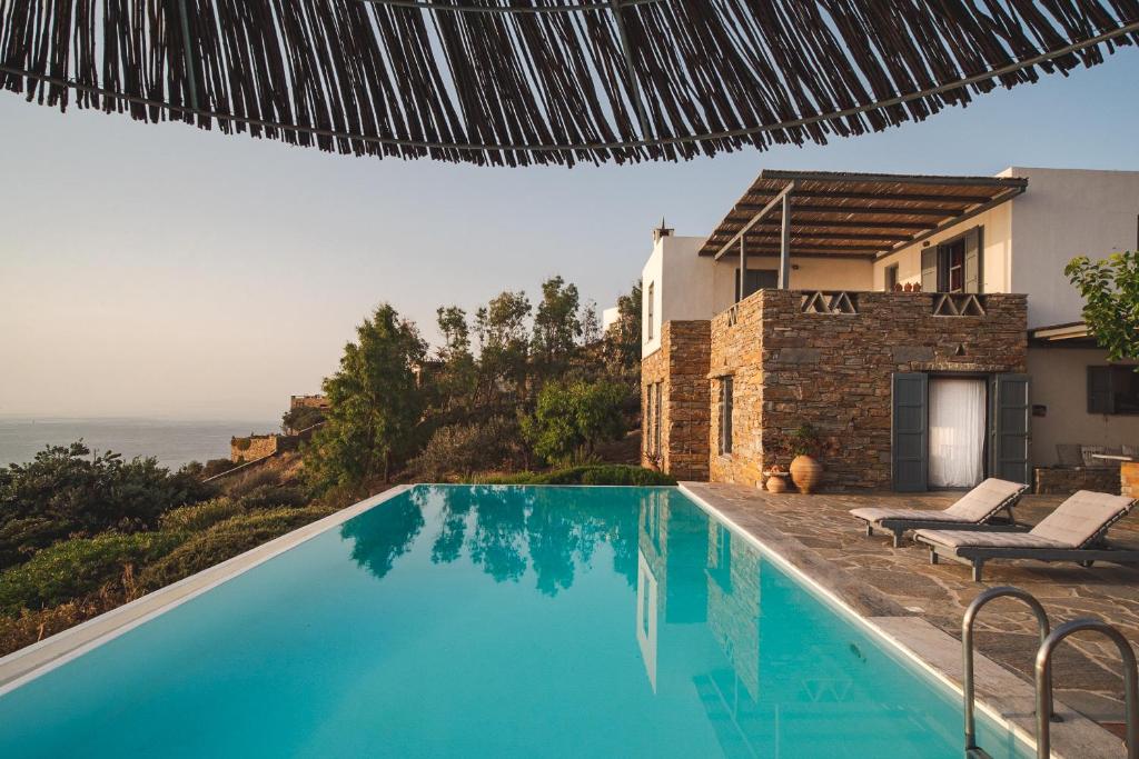 a large blue swimming pool next to a house at Kea Boho Luxury with Pool & Stunning Views in Melissaki