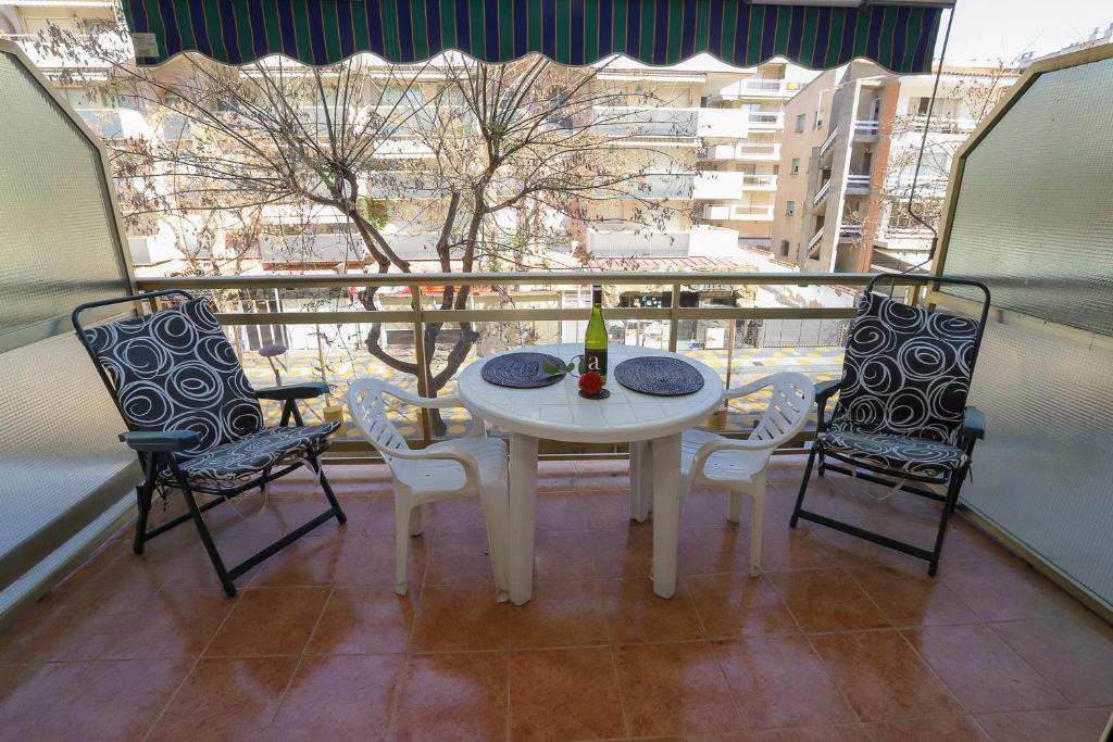 einen weißen Tisch und Stühle auf einem Balkon mit Fenster in der Unterkunft Costa Daurada Apartaments - LA SIRENA in Salou