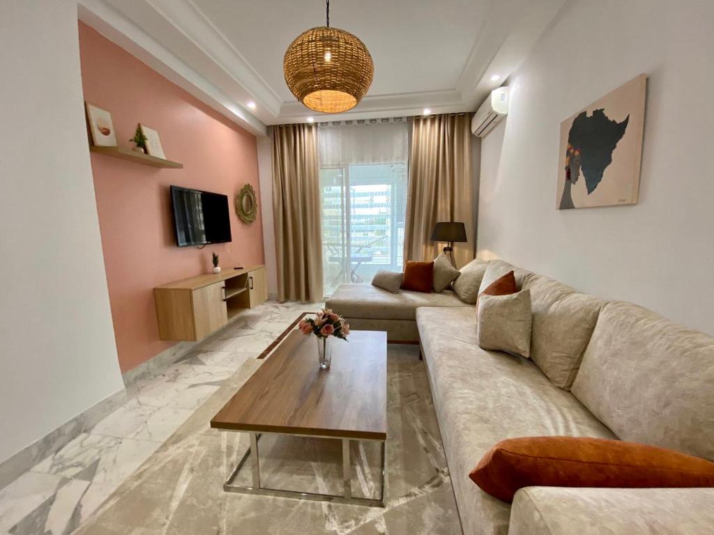 een woonkamer met een bank en een tafel bij Appart calme & chaleureux en résidence près de la mer in Monastir