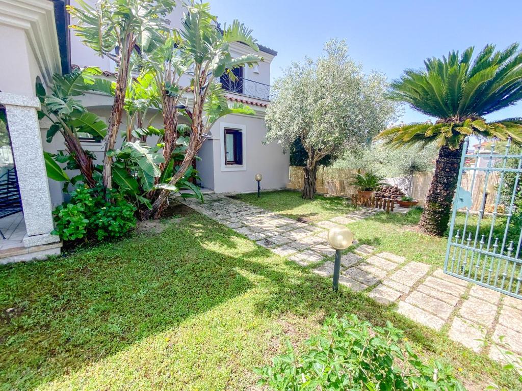 a garden of a house with palm trees and a fence at Casa Sterlizia [Olbia] in Olbia