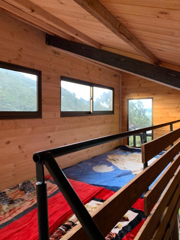 a room with a bed in a cabin with windows at Mirador Bosque Gran Torino Neusa in Cogua