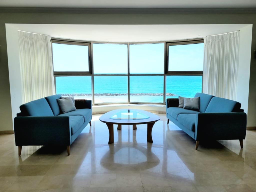 a living room with two blue couches and a table at Panoramic Sea-View Suite in Haifa