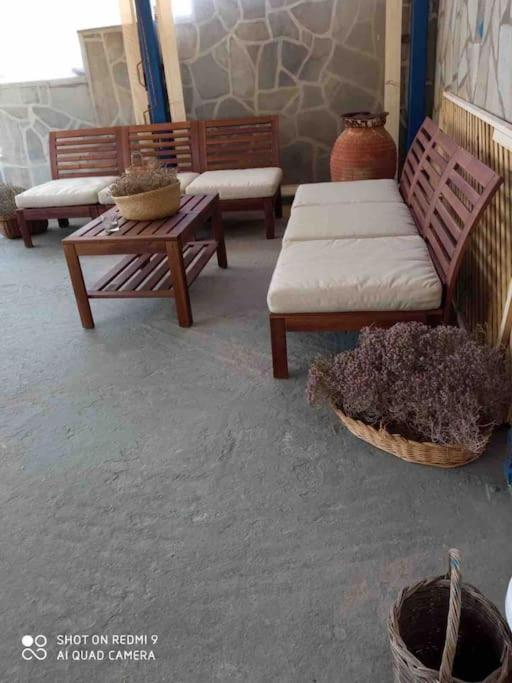 a living room with benches and a table and a basket of plants at Marditsa's House by the sea in Serifos Chora