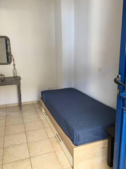 a small bedroom with a blue bed in a room at Marditsa's House by the sea in Serifos Chora