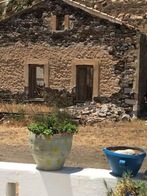 two vases sitting on a table in front of a building at Marditsa's House by the sea in Serifos Chora