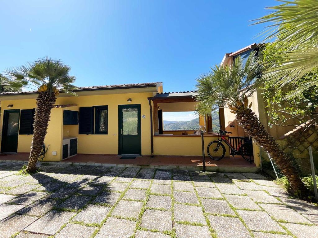 une maison avec deux palmiers devant elle dans l'établissement La Casina di Grassera - Argonauti Vacanze, à Rio nellʼElba