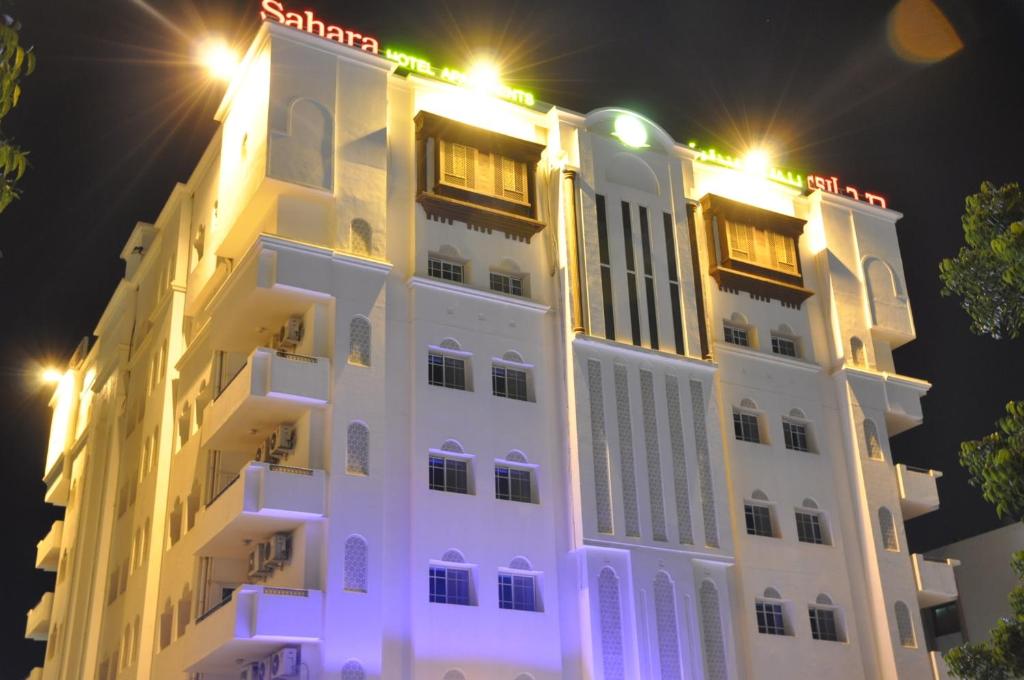 um edifício branco com luzes no topo à noite em Sahara Hotel Apartments em Mascate