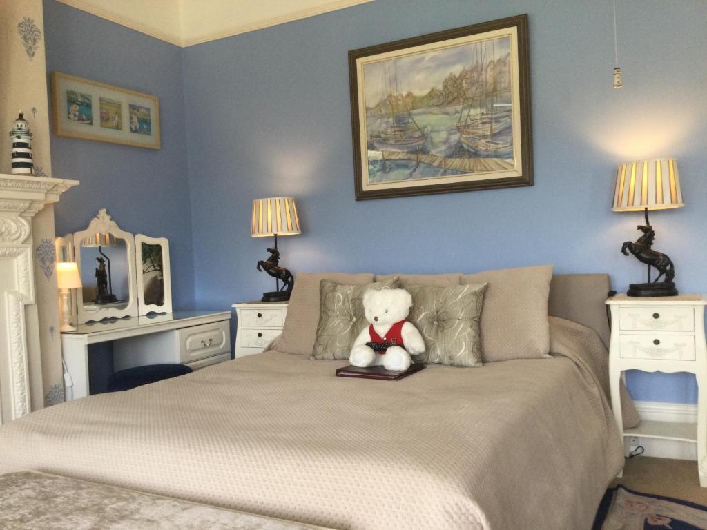 a teddy bear sitting on top of a bed at Arun Sands Rooms in Littlehampton