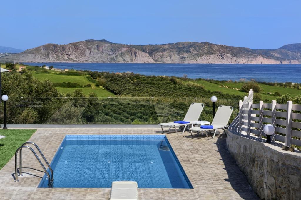 a swimming pool with chairs and a view of the water at Nereid Villa, summer feeling, By ThinkVilla in Episkopí- Rethimno