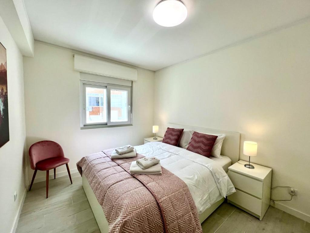 - une chambre avec un lit et une chaise rouge dans l'établissement Tavira Central by Homing, à Tavira