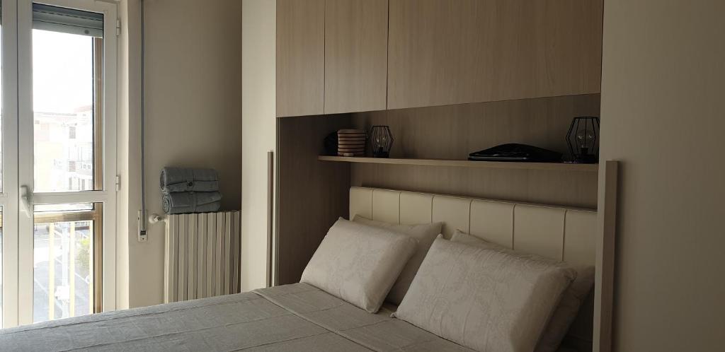 ein Schlafzimmer mit einem Bett mit zwei Kissen und einem Fenster in der Unterkunft Appart terrasse vue mer Tito in Margherita di Savoia
