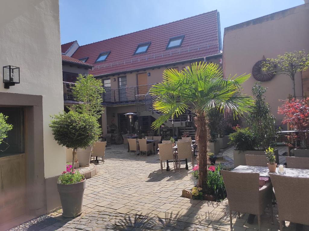 a patio with tables and chairs and trees and plants at Hofgarten Rosa in Ilbesheim