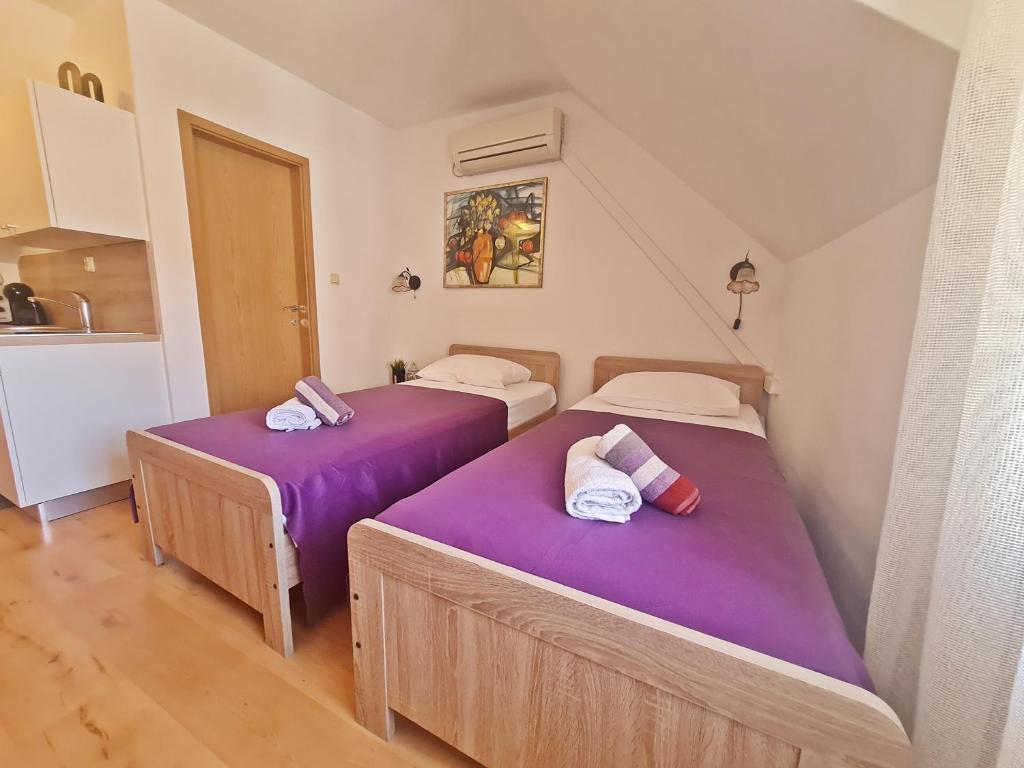 two beds in a small room with purple sheets at City Center Apartments in Split