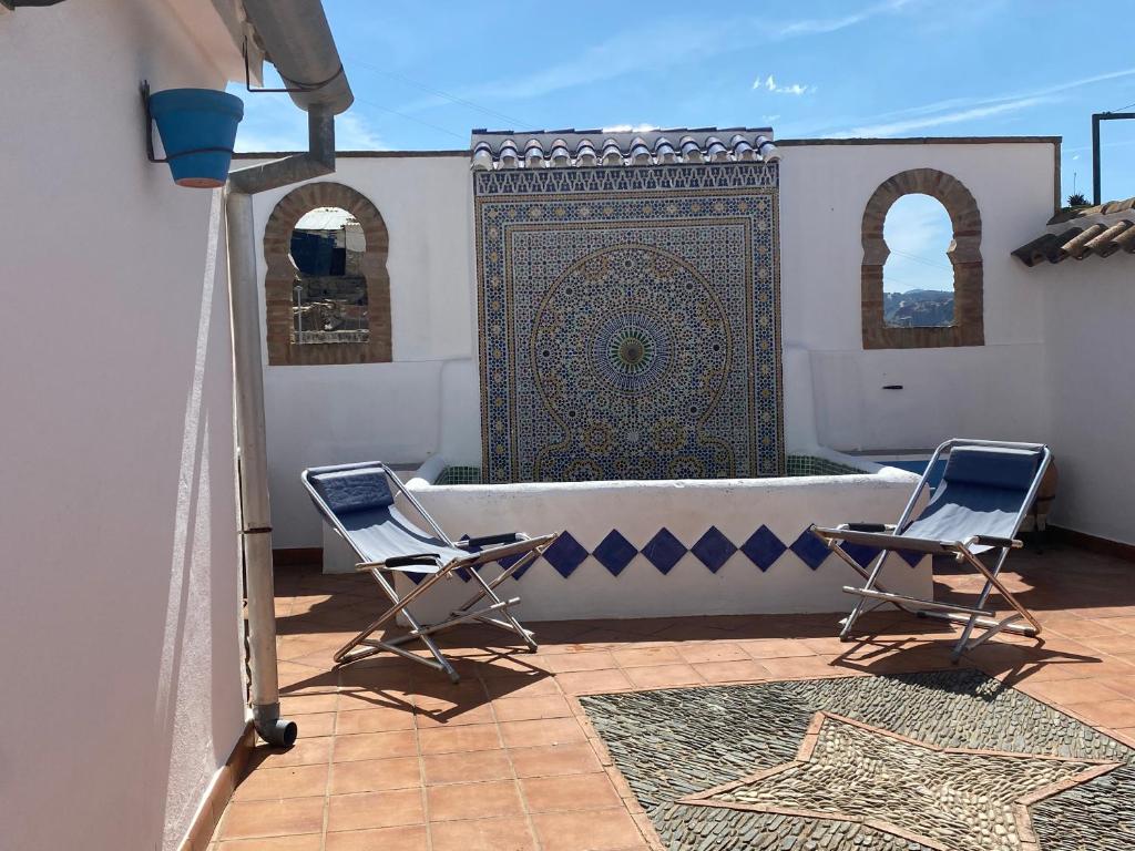 Un patio con dos sillas y una alfombra grande. en Beautiful Traditional town house, en Ardales
