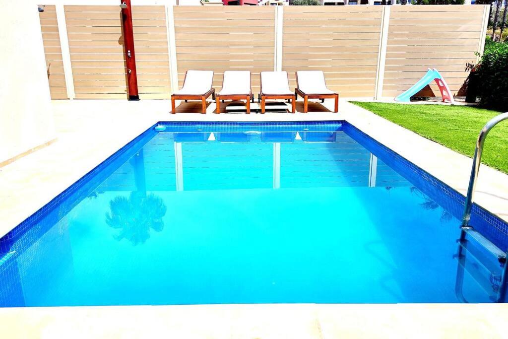 ein Pool mit zwei Liegestühlen daneben in der Unterkunft Villa Valentina in Estepona