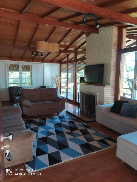 a living room with a couch and a fireplace at Chalé de Vidro Capivari in Campos do Jordão