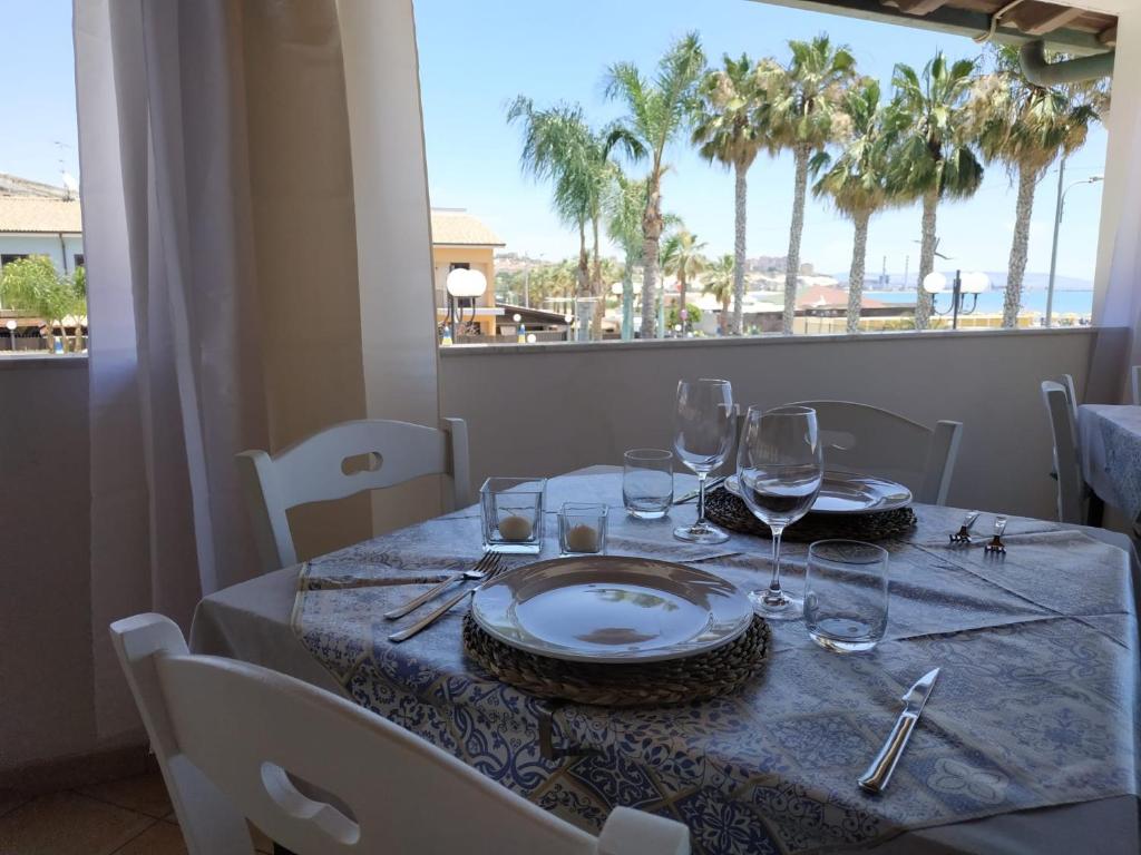 a table with a plate and wine glasses on it at Case Vacanze Ancora in Porto Empedocle