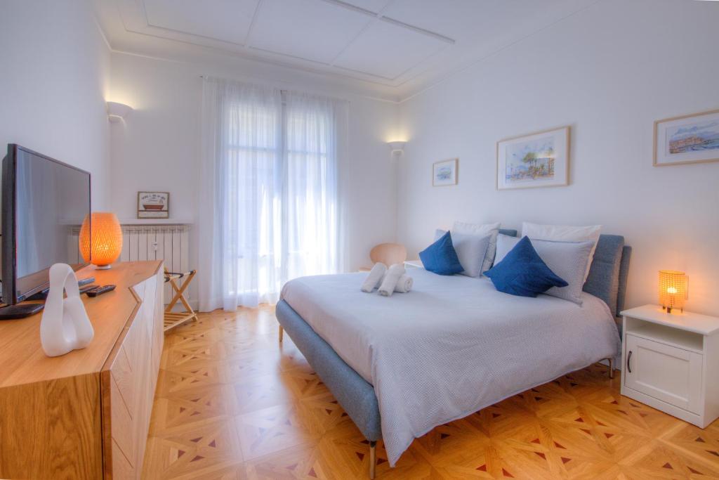 ein Schlafzimmer mit einem Bett mit blauen Kissen und einem TV in der Unterkunft Palais Miramar in Cannes