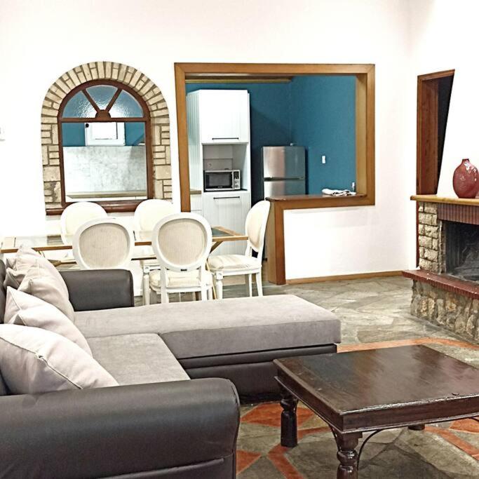 a living room with a couch and a table and a fireplace at ΠΕΤΡΙΝΗ ΚΑΤΟΙΚΙΑ ΣΤΗΝ ΦΥΣΗ in Tagarades