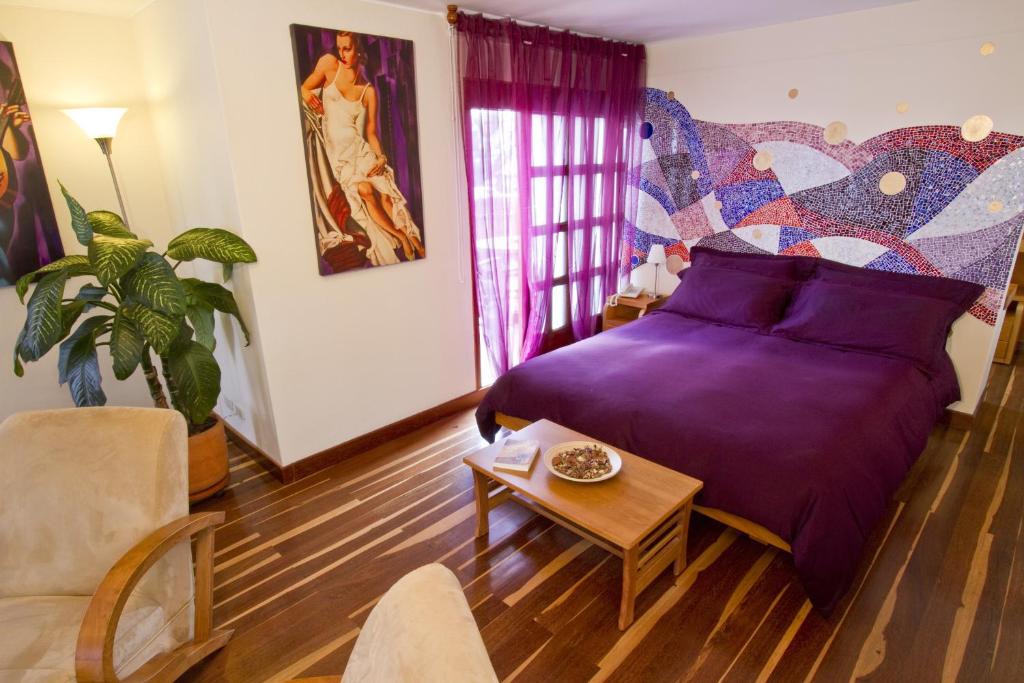 a bedroom with a purple bed and a table at Hotel Casa Deco in Bogotá