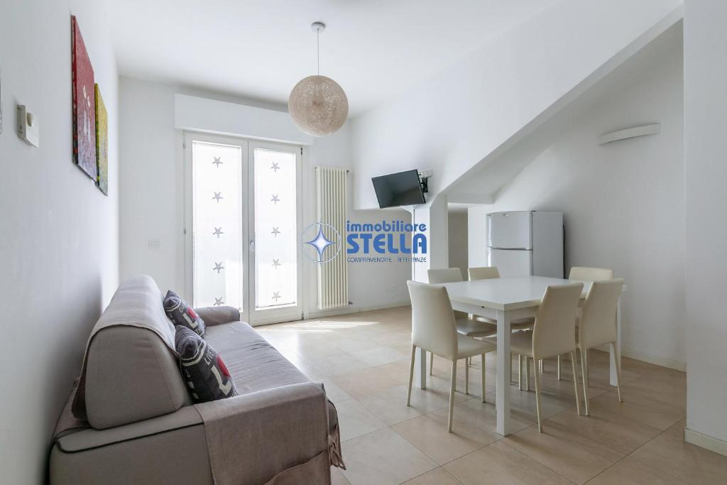 uma sala de estar com um sofá e uma mesa com cadeiras em Condominio Stella em Lido di Jesolo