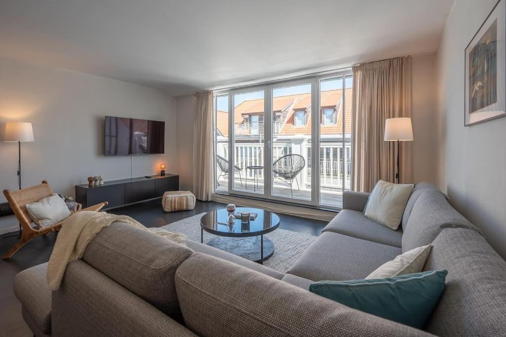 BEACH 52 duplex appartement met terras في كنوك هايست: غرفة معيشة مع أريكة وطاولة