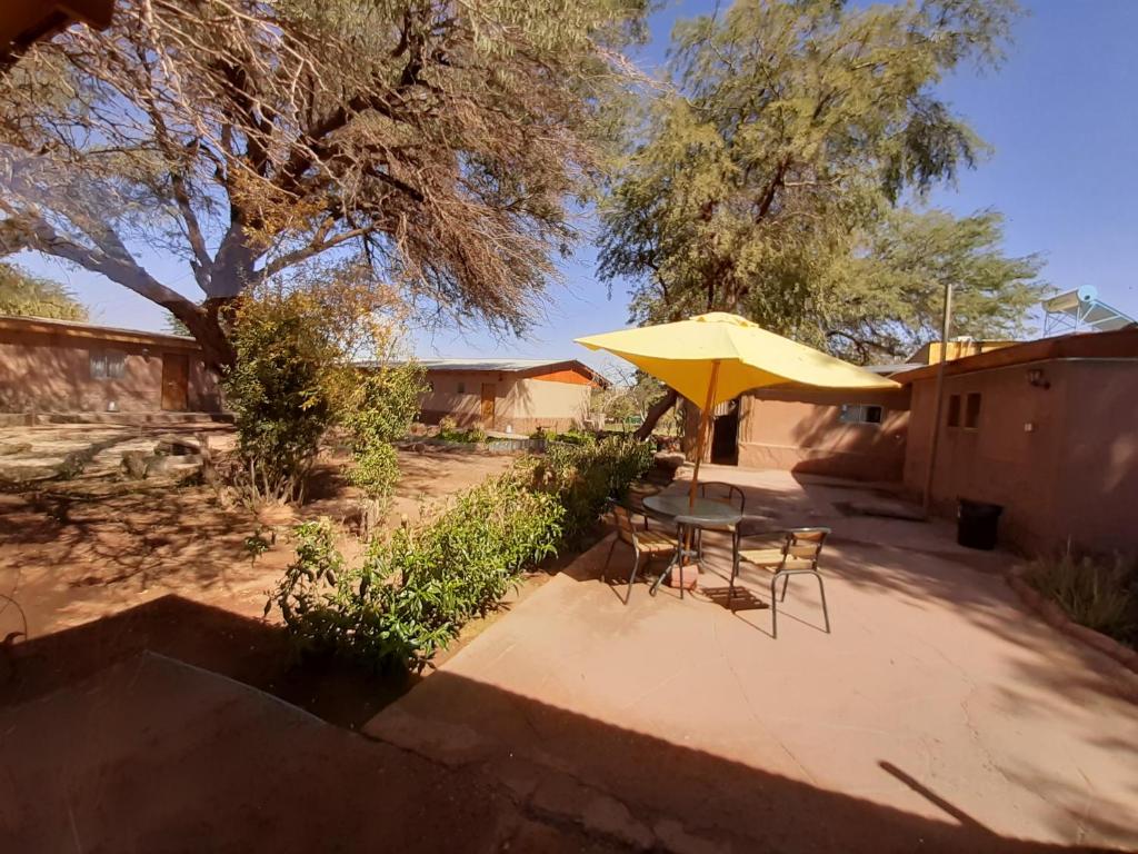 a patio with a table and a yellow umbrella at Inti & Killa Hostal in San Pedro de Atacama