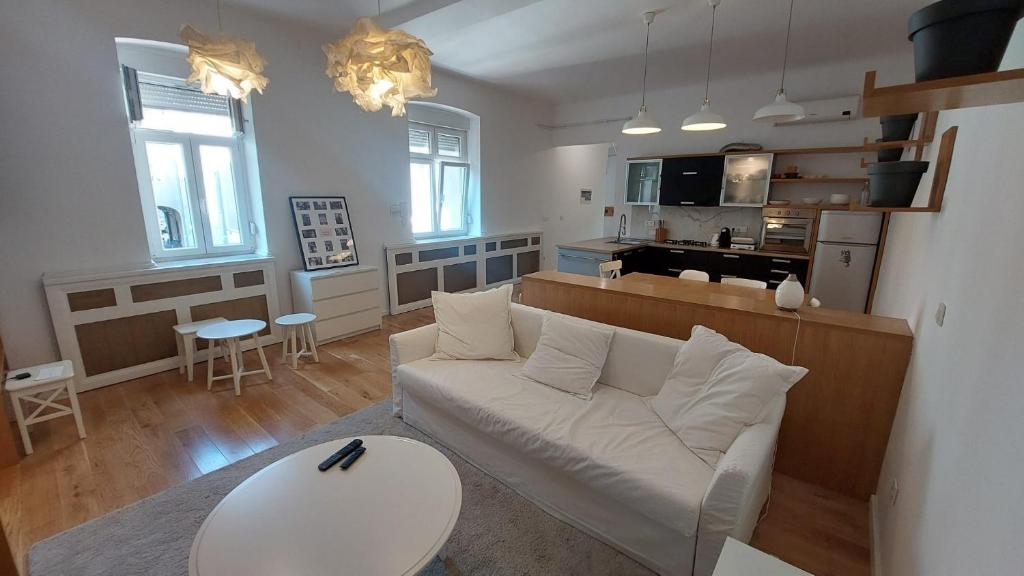 a living room with a white couch and a kitchen at Home S in Zagreb