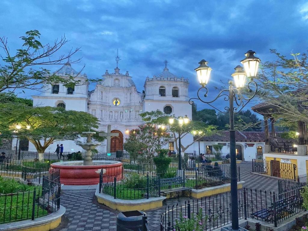 Ciudad Vieja Bed & Breakfast Hotel في غواتيمالا: كنيسة بيضاء كبيرة وامامها نافورة