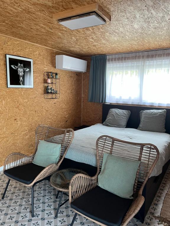 a bedroom with a bed and two wicker chairs at Studio 't Hoveke in Gullegem